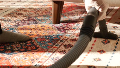 primer plano de una persona aspirando una colorida alfombra oriental