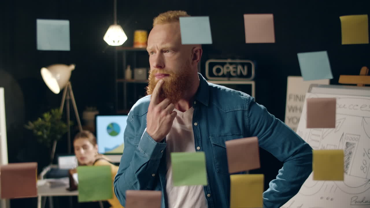 Closeup focused businessman taking off sticker from glass board in night office