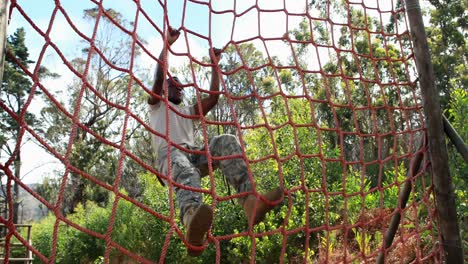 soldado militar subiendo la cuerda durante un curso de obstáculos