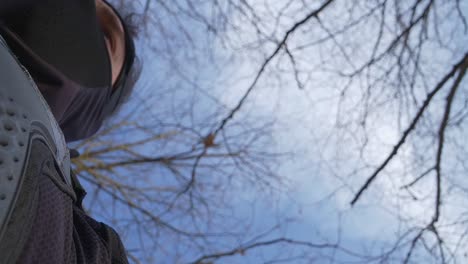 a dramatic low-angle shot of a ninja in black armor gazing at the sky, surrounded by bare tree branches. the cinematic perspective adds mystery and tension, ideal for action and storytelling