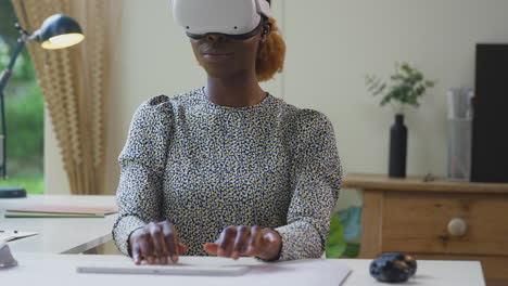 woman working from home office sitting at desk wearing vr headset using ar technology