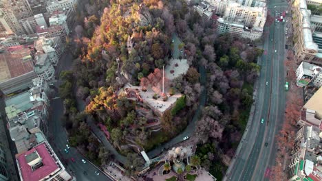 Luftaufnahme-Der-Kaupolicanischen-Terrasse-Am-Santa-Lucia-Hügel,-Bedeckt-Mit-Herbstlichen-Bäumen,-Verkehr-In-Alleen-Bei-Sonnenuntergang,-Santiago,-Chile