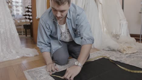 man marking cloth for sewing gown