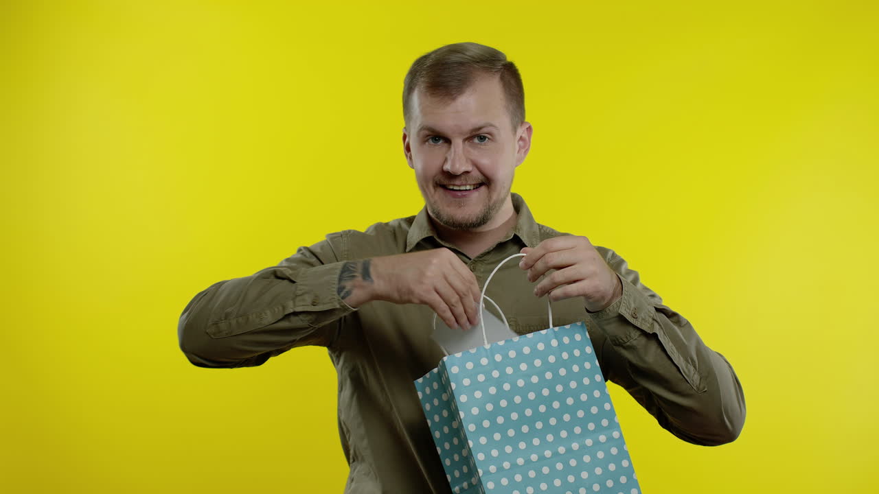 Uomo attraente che mostra la scritta Black Friday da una borsa della spesa, sorridendo e rallegrandosi per gli sconti.