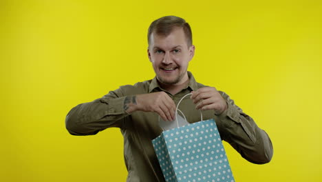 hombre atractivo mostrando la inscripción del viernes negro de la bolsa de compras, sonriendo, regocijándose de los descuentos