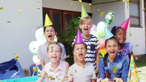 niños con sombreros de fiesta celebrando con animación de confeti sobre globos