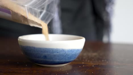 a women slowly pours dry ingredients into a small ornamental bowl creating a smokey dusty haze