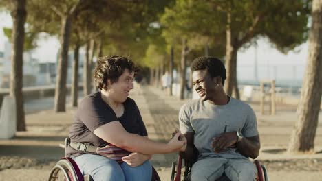 happy friends using wheelchairs greeting and shaking hands