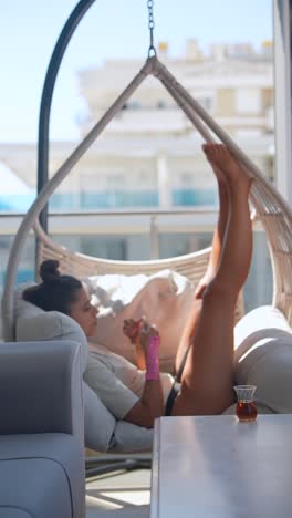 woman relaxing in hanging chair on balcony