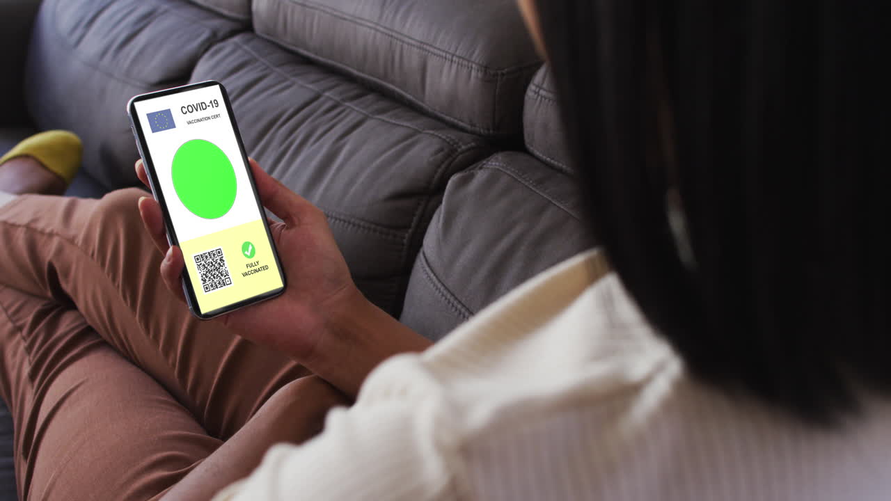 mujer en casa con un teléfono inteligente con certificado de vacunación contra la covid, bandera de la ue y código qr en la pantalla