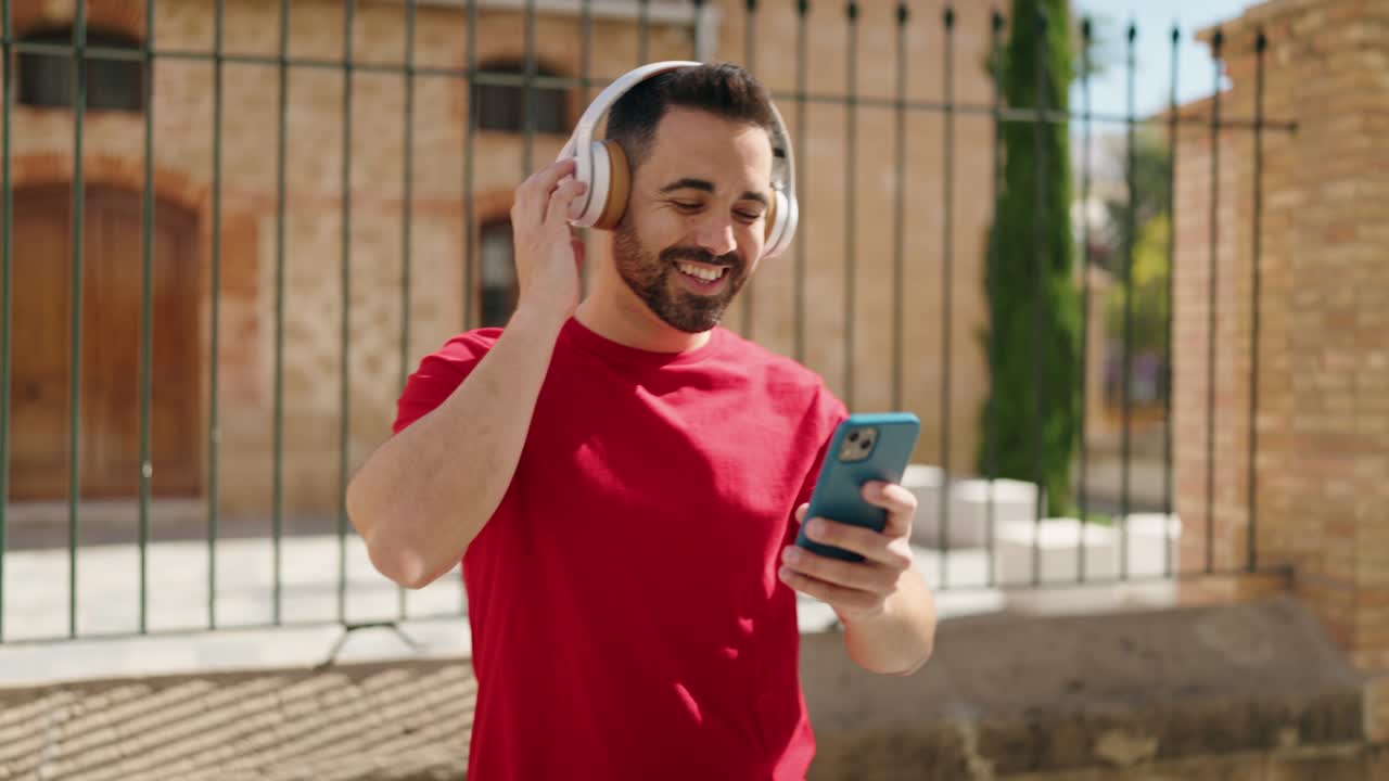 joven hispano sonriendo confiado escuchando música en la calle