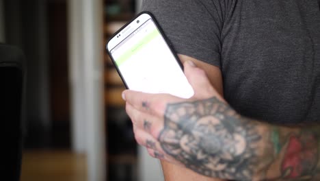 A-young-man-with-diabetes-checks-his-blood-glucose-levels-in-his-home-with-his-smartphone-and-glucose-reading-sensor-on-his-arm