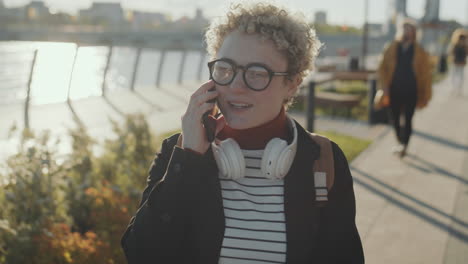 girl with prosthetic arm walking in city and speaking on phone