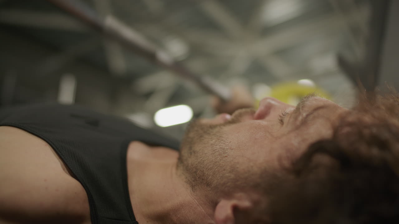 Close-Up of Strong Man Doing Barbell Bench Press Exercise in Gym