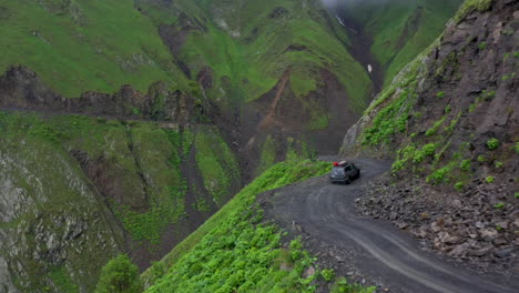 Dramática-Toma-De-Drones-De-Un-Vehículo-Conduciendo-Por-La-Carretera-A-Tusheti,-Una-De-Las-Carreteras-Más-Peligrosas-Del-Mundo.