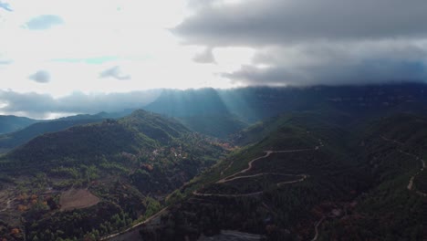 Mountain-view-with-sun-rays-piercing-through-clouds-over-Montserrat-and-Marganell,-Barcelona