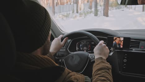 man driving car in winter and chatting on video call