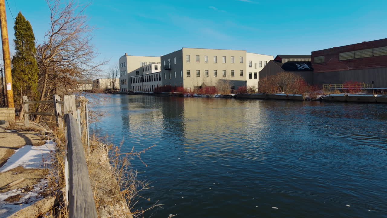 Käsivaralla kuvattu vanha historiallinen paperitehdasrakennus kävelytien varrella kirkkaana talvipäivänä, Fox River Appleton, Wisconsin