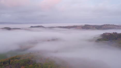 mist covering rural forests of tuscany in italy, aerial