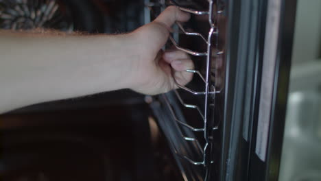 man removes oven rack holder from side of oven