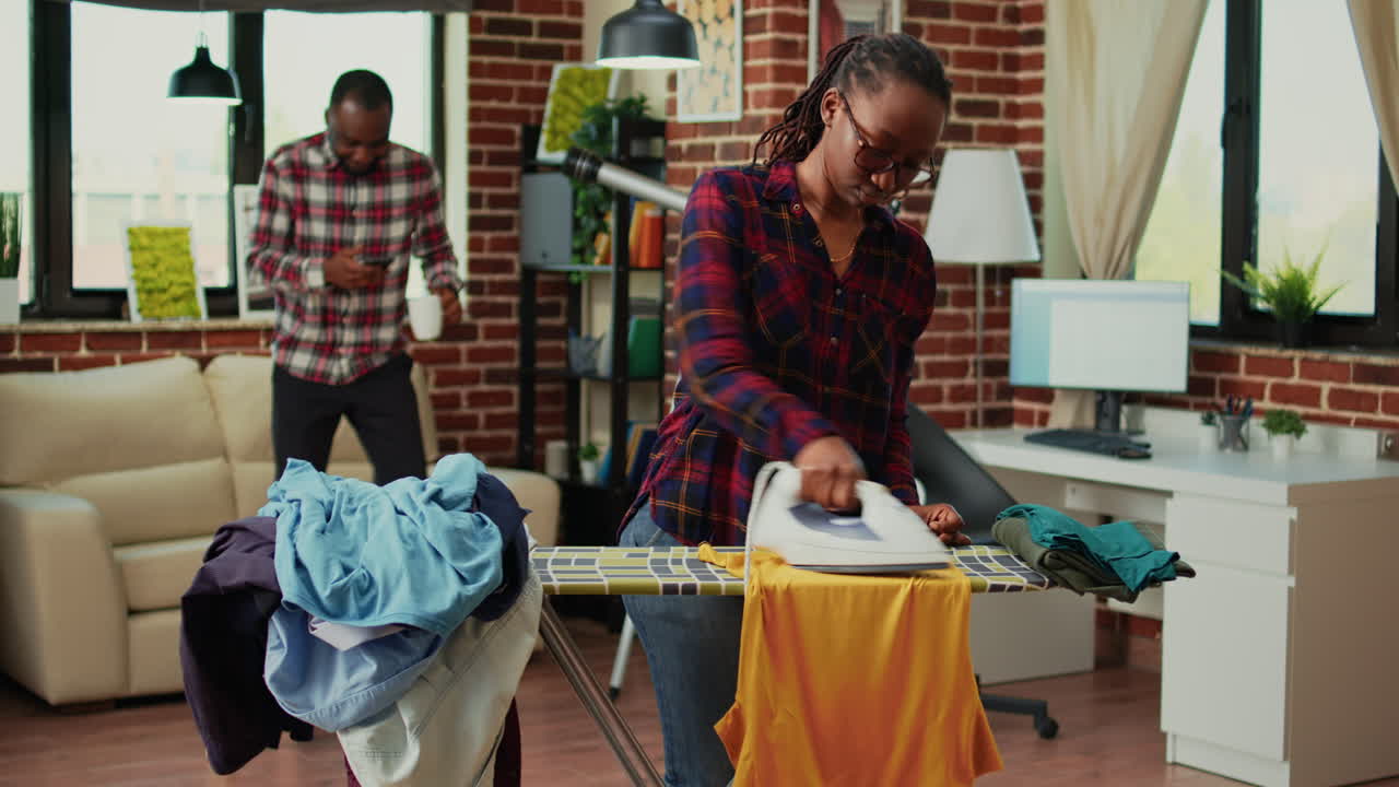 Depressed african american woman ironing laundry
