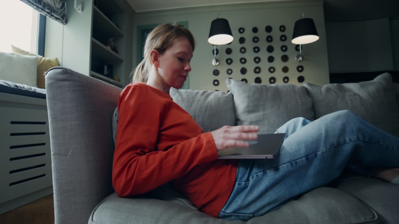 mujer relajándose en un sofá usando una computadora portátil y una tableta