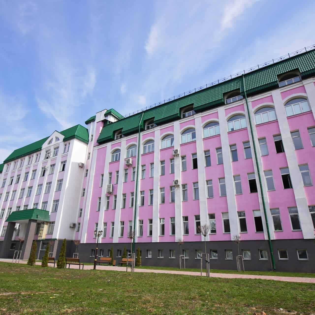 Beautiful pink and white building with green roof. Huge construction with lots of windows and without balconies. Low angle view