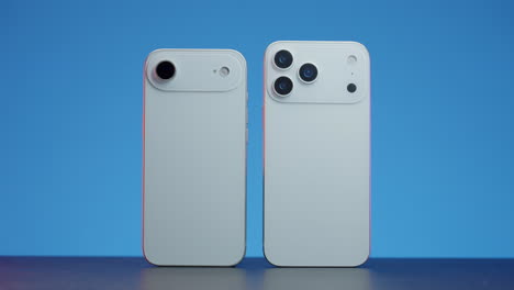 two smartphones with different camera setups on a blue background