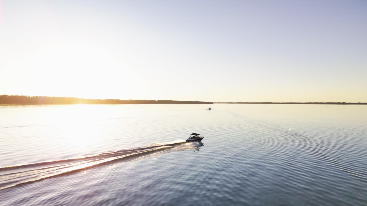 Aerial View of Motorboat Cruising on Lake at Sunset Golden Hour Drone Shot
