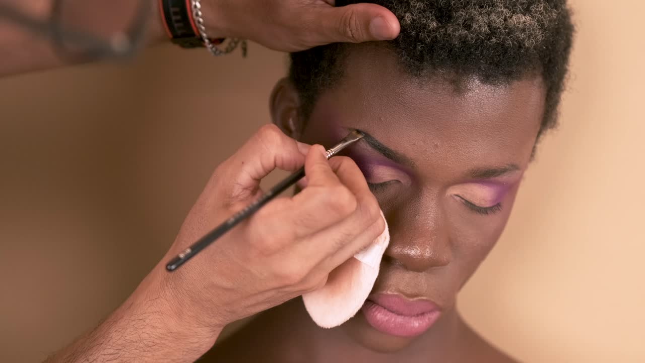 Crop visagiste filling in eyebrows of black transgender