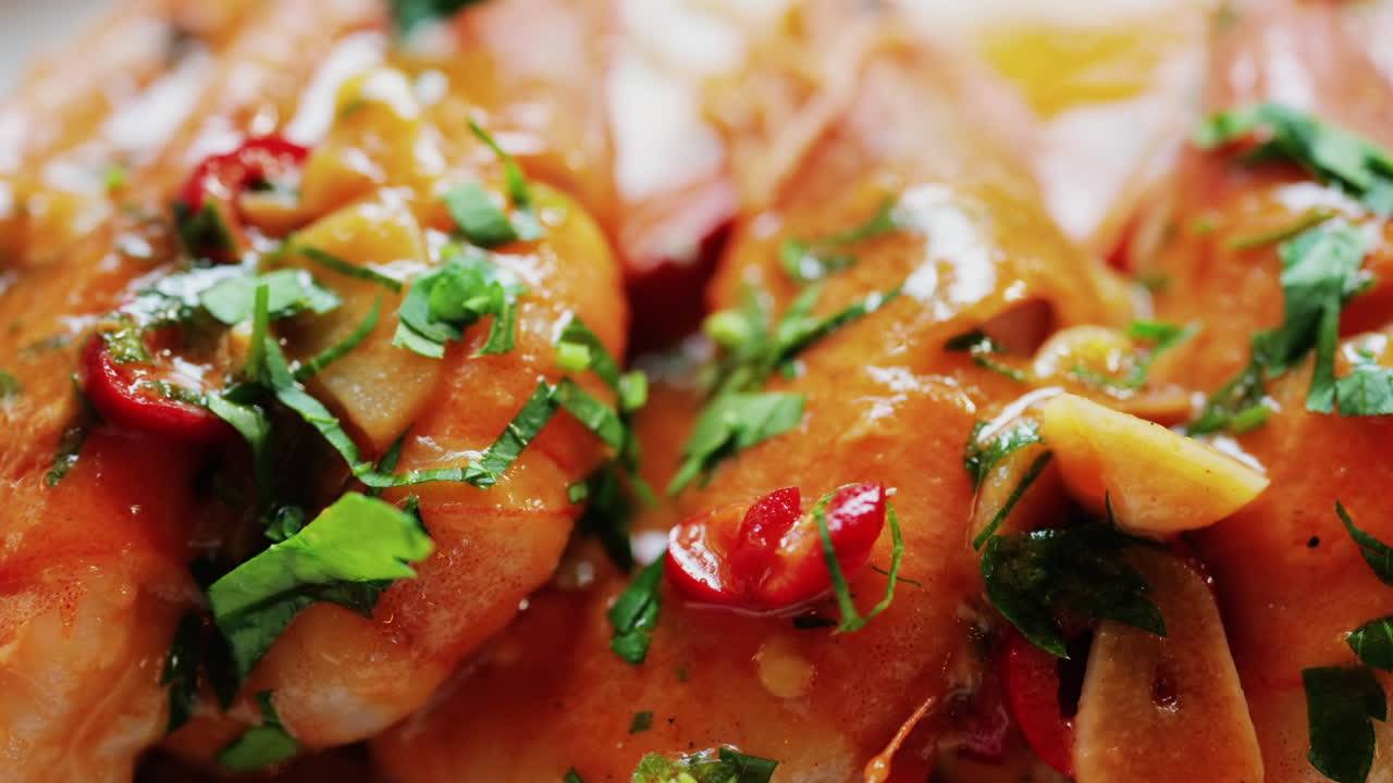 Garlic prawns in a rich sauce topped with herbs on a white plate
