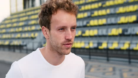 close up of a sportive man resting and drinking water after running workout in the stadium