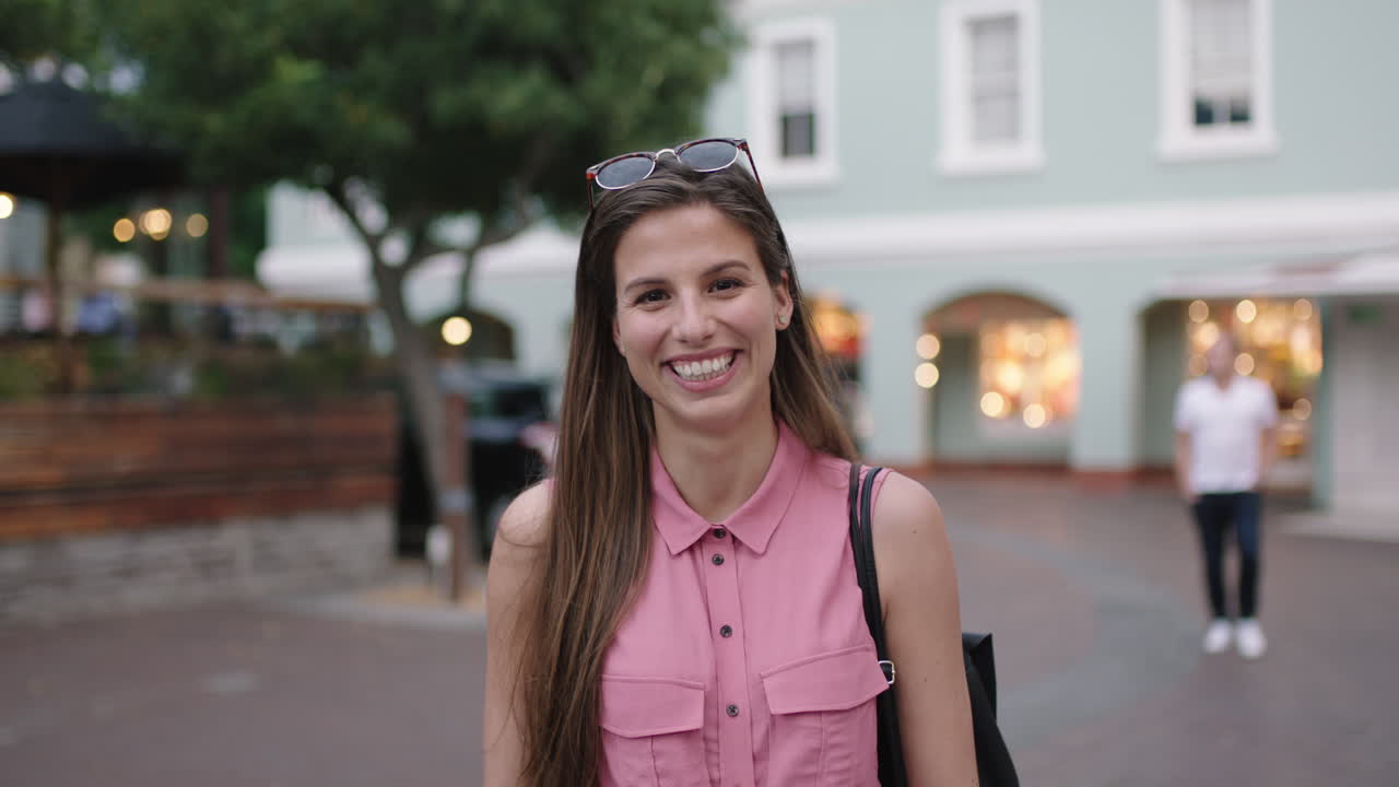 retrato en cámara lenta de una mujer joven y hermosa con blusa rosa riendo alegremente en la cámara de la noche de fondo urbano