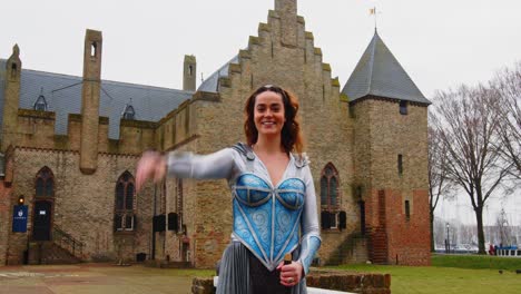 Fantasy-scene:-Beautiful-warrior-princess-standing-in-front-of-castle-and-waving-towards-camera