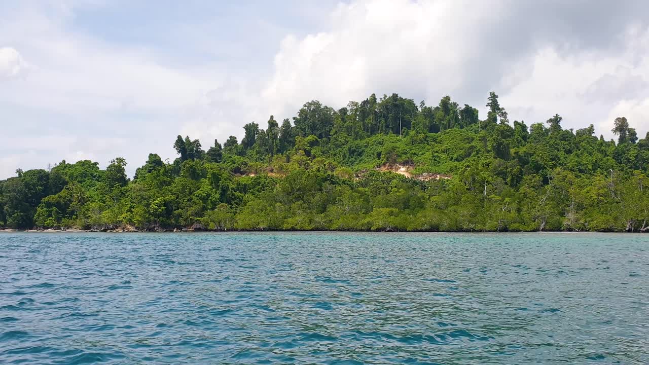 Tropical island with green forest and ocean views in Raja Ampat, West Papua Indonesia from fast moving motorboat
