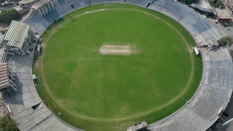 drone zoom out shot of players playing cricket in stadium of gujranwala during daytime in punjab, pakistan