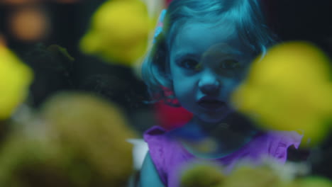 little girl looking at fish in aquarium curious child watching colorful sea life swimming in tank learning about marine animals in underwater ecosystem inquisitive kid at oceanarium