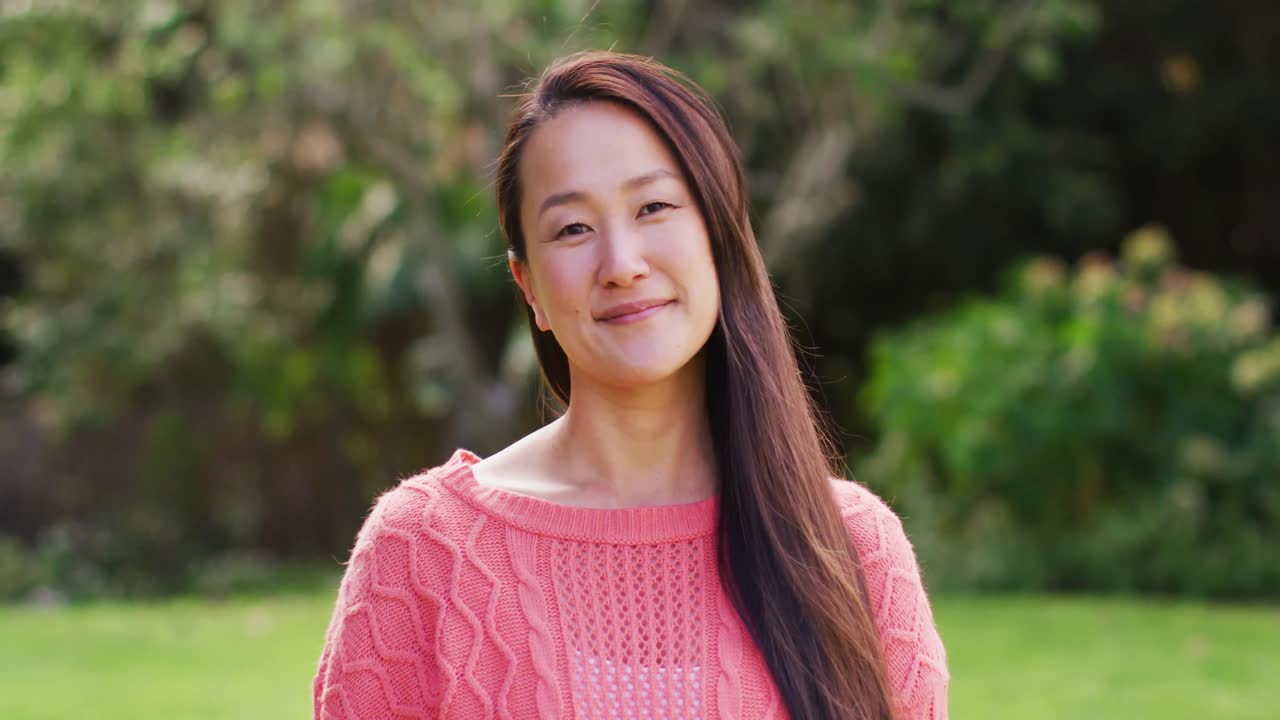 행복 한 아시아 여자 의 초상화 는 정원 에서 미소 짓고 웃고 있는 카메라 를 보고 있다