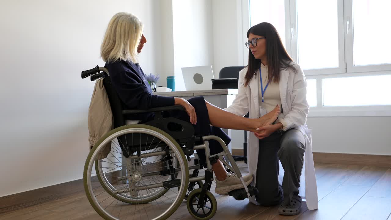 Doctor examining elderly woman's leg in wheelchair