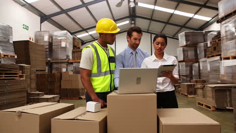 gerentes de almacén y trabajadores mirando la computadora portátil