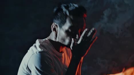 hombre en postura de oración junto al fuego