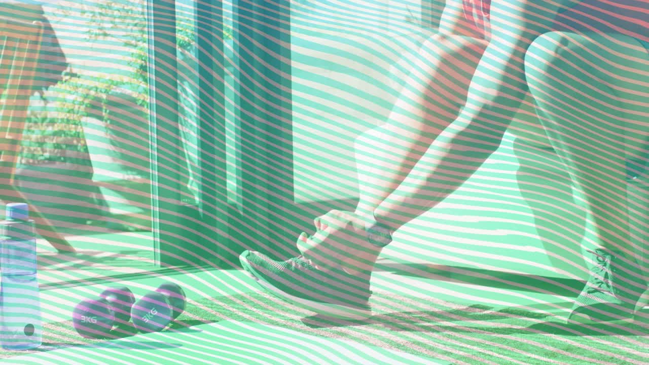 ドアの開口部近くで、靴ひもを締めながらかがみ込み、ウェイトを使った自宅トレーニングの準備をする男性。