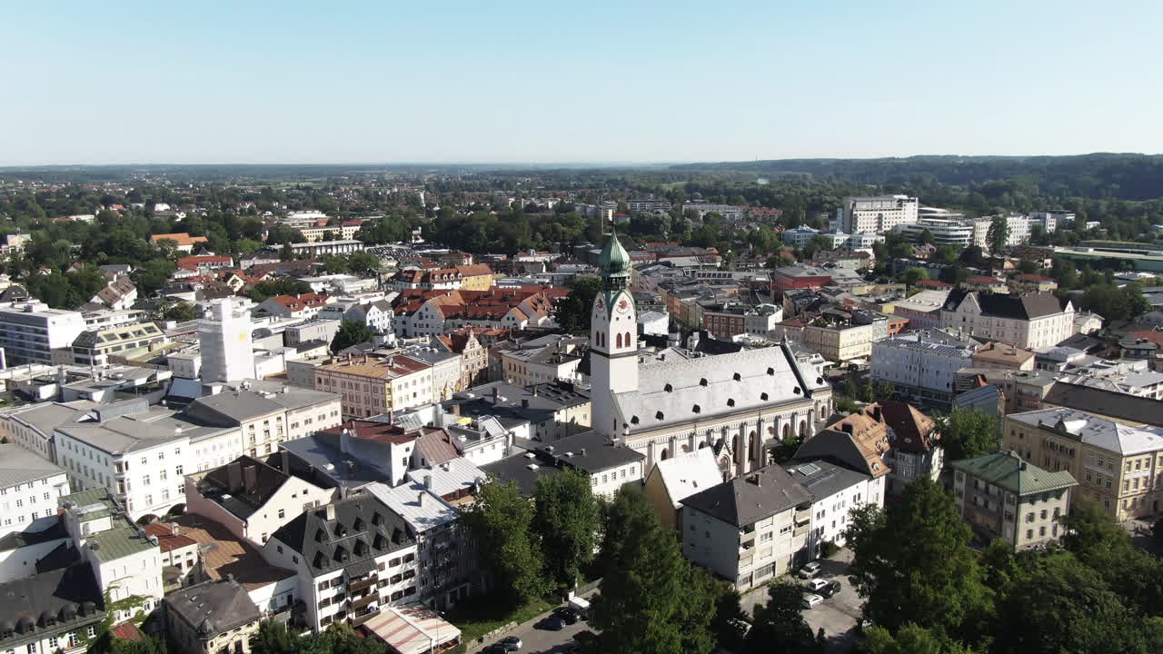 Aerial shot of the city of Rosenheim showing the NeogothicSt. Nikolaus Church flying backwards revealing thebeautiful old town with it’s parks, restaurants and thepedestrian zone.