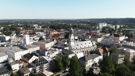 aerial shot of the city of rosenheim showing the neogothicst. nikolaus church flying backwards revealing thebeautiful old town with it’s parks, restaurants and thepedestrian zone.