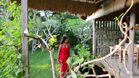 beautiful asian girl walking through tropical garden towards villa entrance in bali during morning golden hour