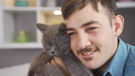 hombre besando y abrazando a su gato gris.