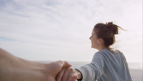 pov of young couple holding hands woman leading boyfriends walking towards sunset on empty beach