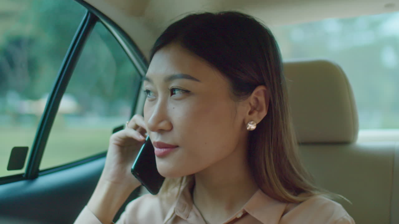 Asian Businesswoman Chatting on Phone in Taxi