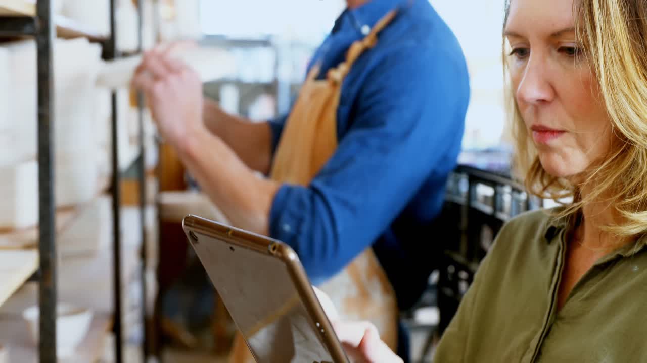 Vrouwelijke pottenbakker gebruikt digitale tablet 4k