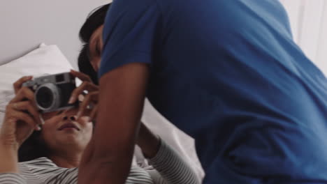 pareja feliz tomando fotos juntos usando la cámara divirtiéndose en casa en la cama jugando disfrutando de una relación romántica fotografiándose el uno al otro